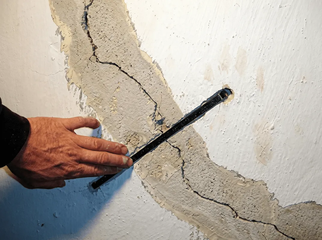 A wall with a large crack is being inspected by a professional in Irvine, CA